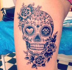 a woman's thigh with a skull and roses tattoo on it