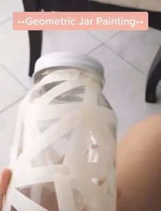 someone holding up a jar with white tape on it and the words geometric jar painting