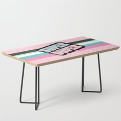 a wooden table with black metal legs and a pink, blue, yellow and green striped design