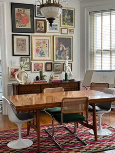 a dining room table with chairs and pictures on the wall