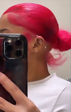 a woman with pink hair taking a selfie in front of her cell phone camera