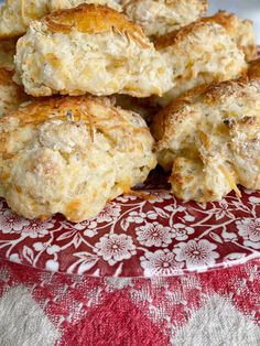 biscuits are piled on top of each other on a red and white plate with floral tablecloth