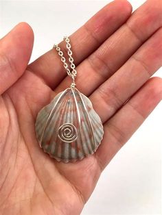 a hand holding a small silver shell with a spiral design on it's side