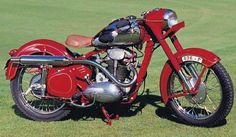 a red motorcycle parked on top of a lush green field