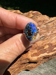 Another gorgeous pattern Koroit boulder opal with a lot going on...this is one of those opals where the more you look, the more you see.  Reminds me of a dragon's egg💙 This stone is 18 x 13 mm or approximately .75 x .5 inches and is set in a sterling silver bezel setting.  Since the stone is statement sized, I designed it with a  double half round band, size 6 but will fit more like a 5.75.   Boulder opals are mined from ironstone boulders under the ground.  The opal is formed from a solution of silicon dioxide and water.  As the water runs through the earth, it picks up silica from sandstone a day carries this silica-rich solution into cracks and voids, caused by natural faults or decomposing fossils.  As the water evaporates, it leaves behind a silica deposit, which can be found in one Unique Oval Opal Ring For Healing, Unique Collectible Opal Ring, Collectible Unique Opal Ring, Unique Oval Cabochon Opal Ring, Spiritual Oval Opal Ring, Unique Iridescent Opal Ring, Unique Cabochon Opal Ring For Collectors, Blue Cabochon Opal Ring Gift, Spiritual Multi-stone Opal Ring