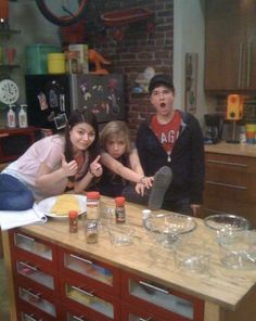 three people standing in front of a kitchen counter