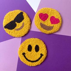 three yellow smiley face coasters with hearts and sunglasses on purple and pink geometric background