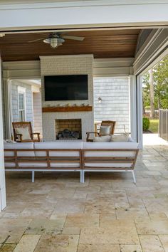 a covered patio with two chairs and a fireplace