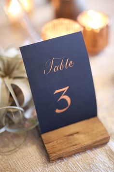 a table number is placed on top of a wooden stand with candles in the background