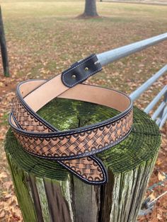 a brown and black leather belt sitting on top of a wooden post