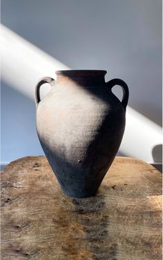 a black vase sitting on top of a wooden table