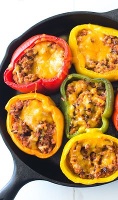 stuffed bell peppers on a black plate with cheese