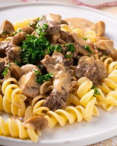 a white plate topped with pasta and mushrooms