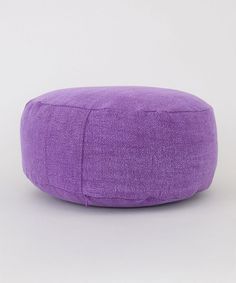 a purple round ottoman sitting on top of a white floor