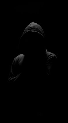 a person in the dark with their hood up