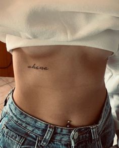 a woman's stomach with the word shame tattooed on her lower side ribcage