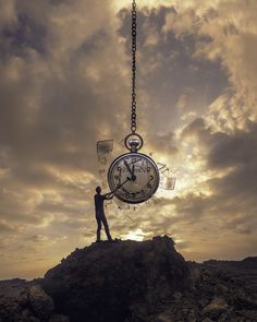 a man standing on top of a rock with a clock hanging from it's side