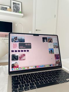 an open laptop computer sitting on top of a white bed next to a wall mounted tv