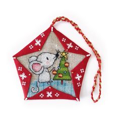 a red ornament with a christmas tree on it and a mouse hanging from the star