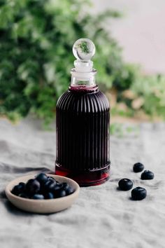 a bottle of liquid sitting on top of a table next to blueberries