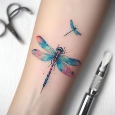 a dragonfly tattoo on the arm