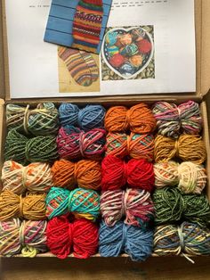 a box filled with lots of different colored yarn next to a piece of paper on top of a table