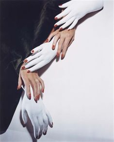 two hands with white and red manicures are holding each other's arms