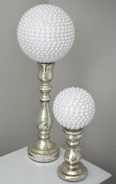 two silver candlesticks sitting on top of a white table next to each other