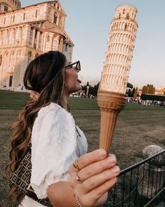 a woman holding an ice cream cone in front of the leaning tower of pisa, italy