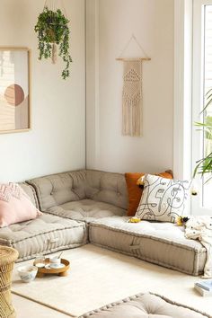 a living room filled with furniture and pillows on top of a white floor next to a window