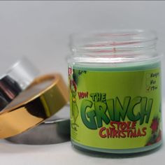 a glass jar filled with green and gold colored candles next to a metal container that says how the grin stole christmas