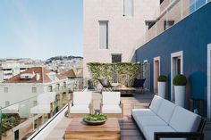 an outdoor living area with white couches and wooden coffee table on the roof terrace