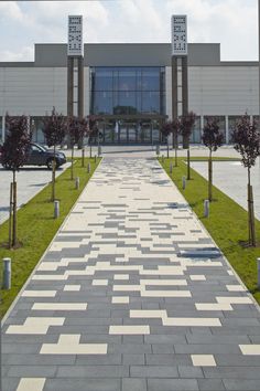 an empty walkway leading to a building with trees and bushes on both sides in front of it