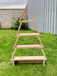 a wooden christmas tree sitting in the grass