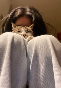 a woman with her legs crossed and a cat laying on her head behind her back