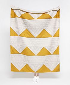 a woman standing in front of a yellow and white quilt