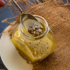 a spoon in a jar filled with food on top of a white and blue plate