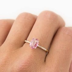 a woman's hand with a pink diamond ring on her left hand and white background