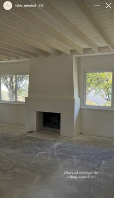 an empty room with two windows and a fire place in the center is seen on this screen