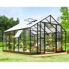 a green house sitting on top of a lush green field with lots of plants in it