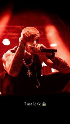 a man with tattoos on his arm holding a microphone in front of red lights and the words last leak