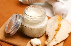 a jar of cream sitting on top of a wooden cutting board next to a sandwich