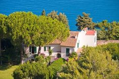 an aerial view of a house with trees and water in the background