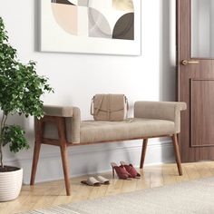 a wooden bench sitting next to a potted plant on top of a hard wood floor