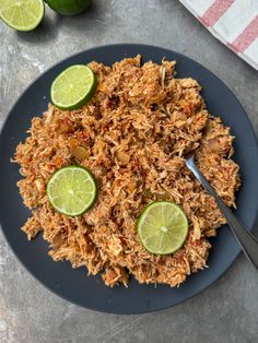 a blue plate topped with rice and limes on top of a table next to sliced limes