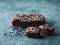 two pieces of chocolate cake sitting on top of a cooling rack next to each other