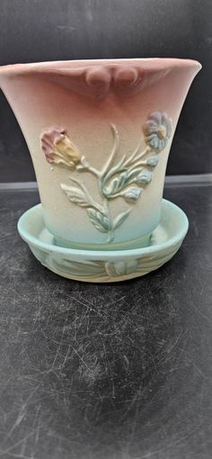 a pink and blue bowl with flowers on the side sitting on a black counter top