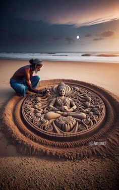 a man sitting on top of a sandy beach next to an intricate sand art piece