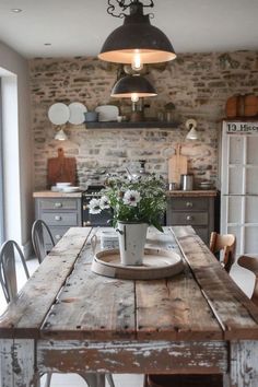 a wooden table topped with a potted plant next to a light hanging over it