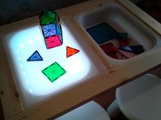 a wooden table topped with lots of different colored rubs on top of white chairs